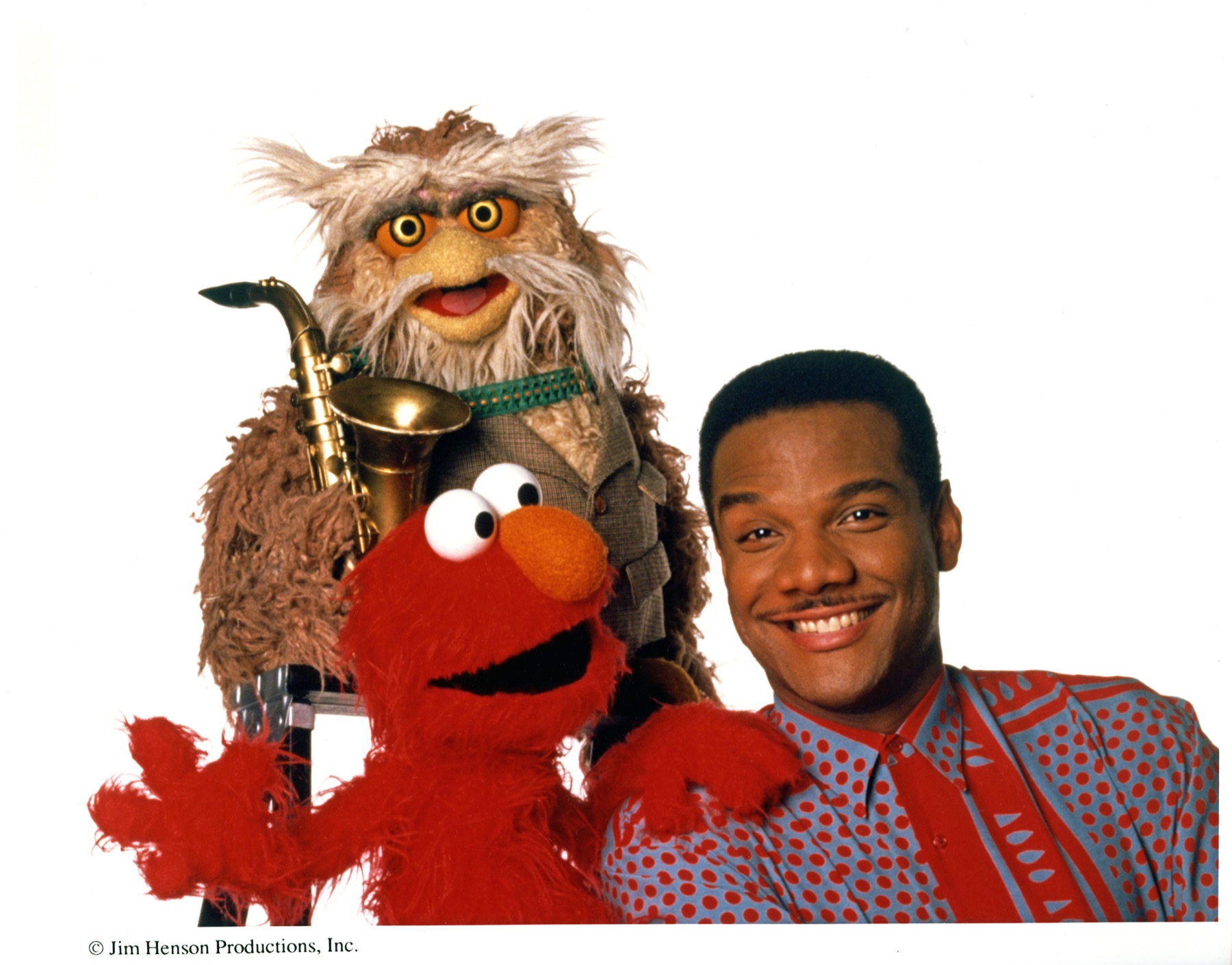 Kevin Clash smiling with two beloved puppet characters